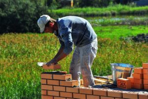 muratore mentre fabbrica un muro