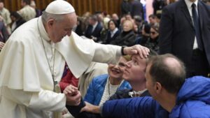 Francesco accarezza un malato durante un'udienza generale in Aula Paolo VI (Vatican Media)